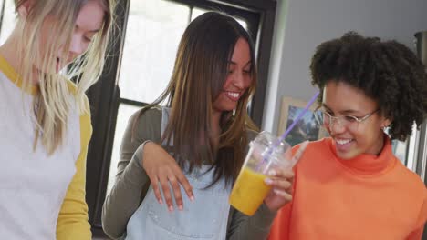 happy diverse teenager girls friends preparing healthy drink in kitchen, slow motion