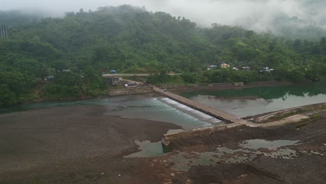 Aliviadero-De-La-Presa-Bajo-El-Puente-De-La-Carretera-Con-Montañas-Neblinosas-Al-Fondo-En-Catanduanes,-Filipinas