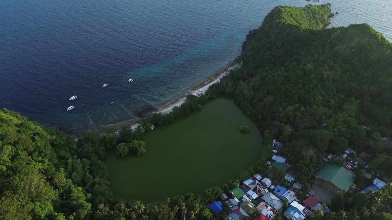 Veduta aerea con drone di una laguna tropicale sull'isola di Apo, Filippine, circondata da lussureggianti colline verdi e oceano con acqua turchese vibrante. Filmato cinematografico 4K ideale per video di viaggio e paradisiaci