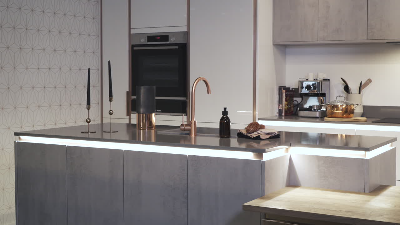 Sliding shot of grey kitchen with LED under-lighting and copper tap