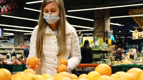 a european woman chooses oranges in a hypermarket. a young woman is shopping, she buys fresh fruit.