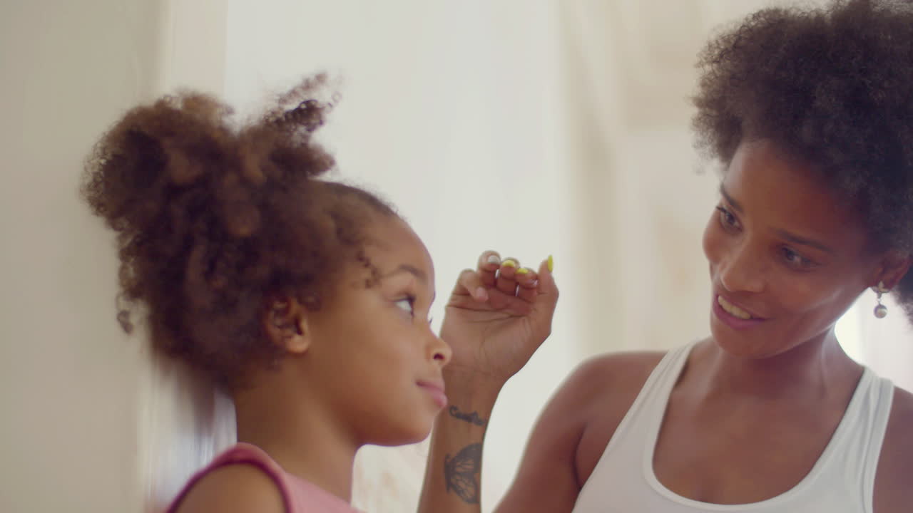 벽에서 딸의 키를 측정하는 웃는 흑인 여성의 클로즈업