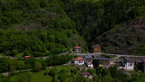a narrow road curves through dense greenery and passes by colorful homes tucked into the cliffside. shot at malonno, italy (italia)