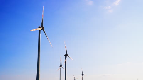 wind turbines against a blue sky. rows of wind turbines stand tall in an open landscape, harnessing renewable energy under a clear blue sky