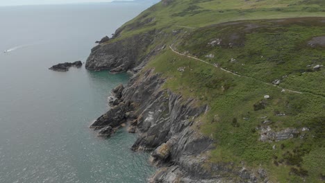 Rocky-Cliffs-Mountain-In-Der-Nähe-Des-Meeres-An-Einem-Strahlend-Blauen-Und-Sonnigen-Tag-Mit-Booten,-Die-Vor-Der-Küste-Segeln