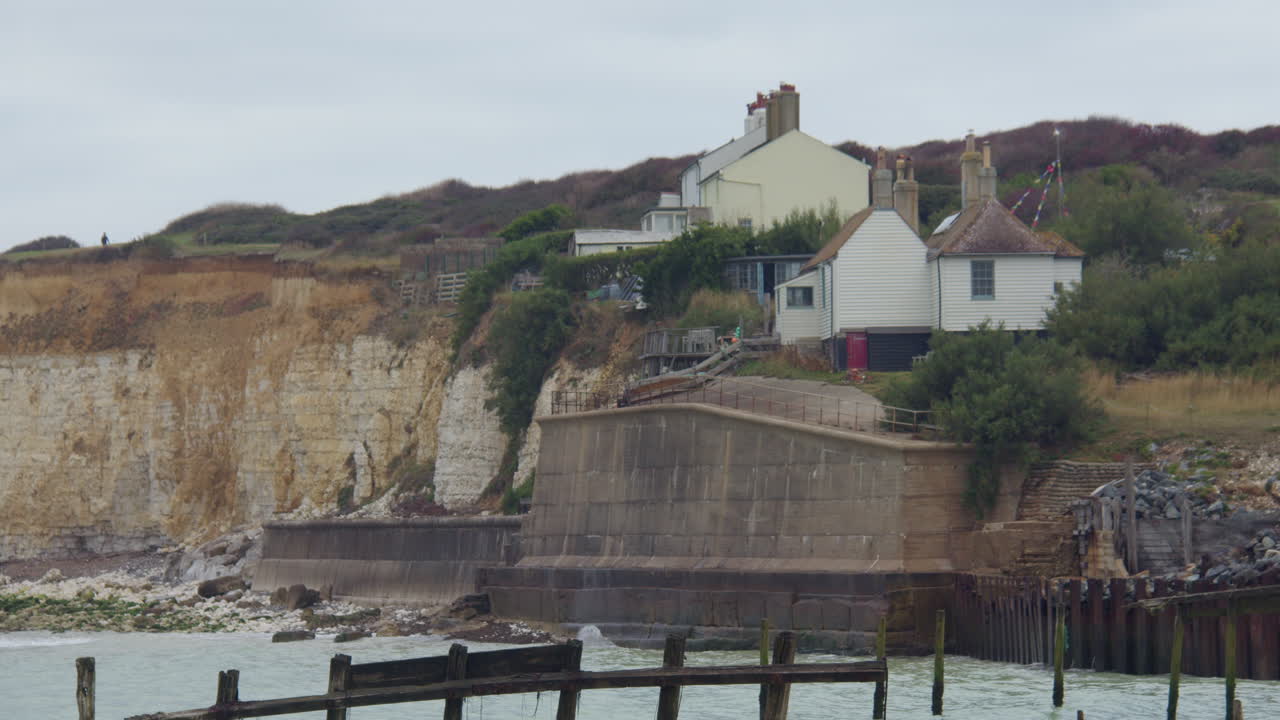 Totalbillede med udsigt over Cuckmere Haven strand mod Seaford Head, med hytter på klippekanten.