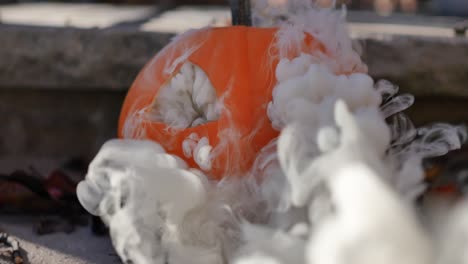 Grey-smoke-coming-out-of-a-jack-o-lantern-sitting-on-steps-atop-dead-fall-leaves