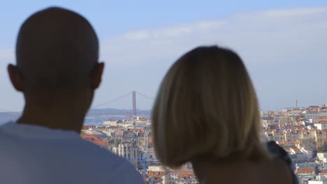 Tourists-admiring-the-view-from-La-Senora-del-Monte-in-Lisbon-Portugal,-beautiful-rooftops-and-The-Vasco-da-Gama-Bridge-in-the-distance