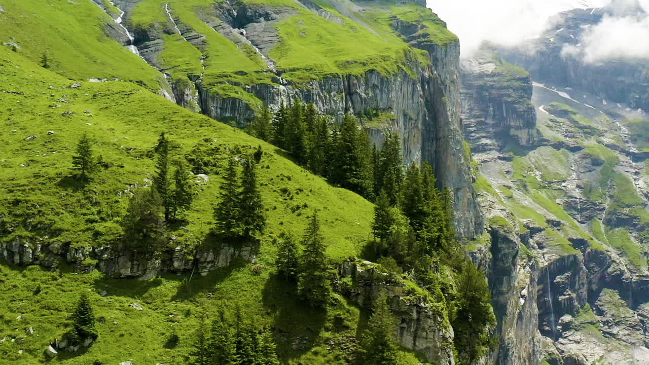 volando sobre hermosas y verdes montañas en suiza con una pequeña casa ubicada en la ladera