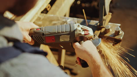 hands of blacksmith grinding metal detail with power tool