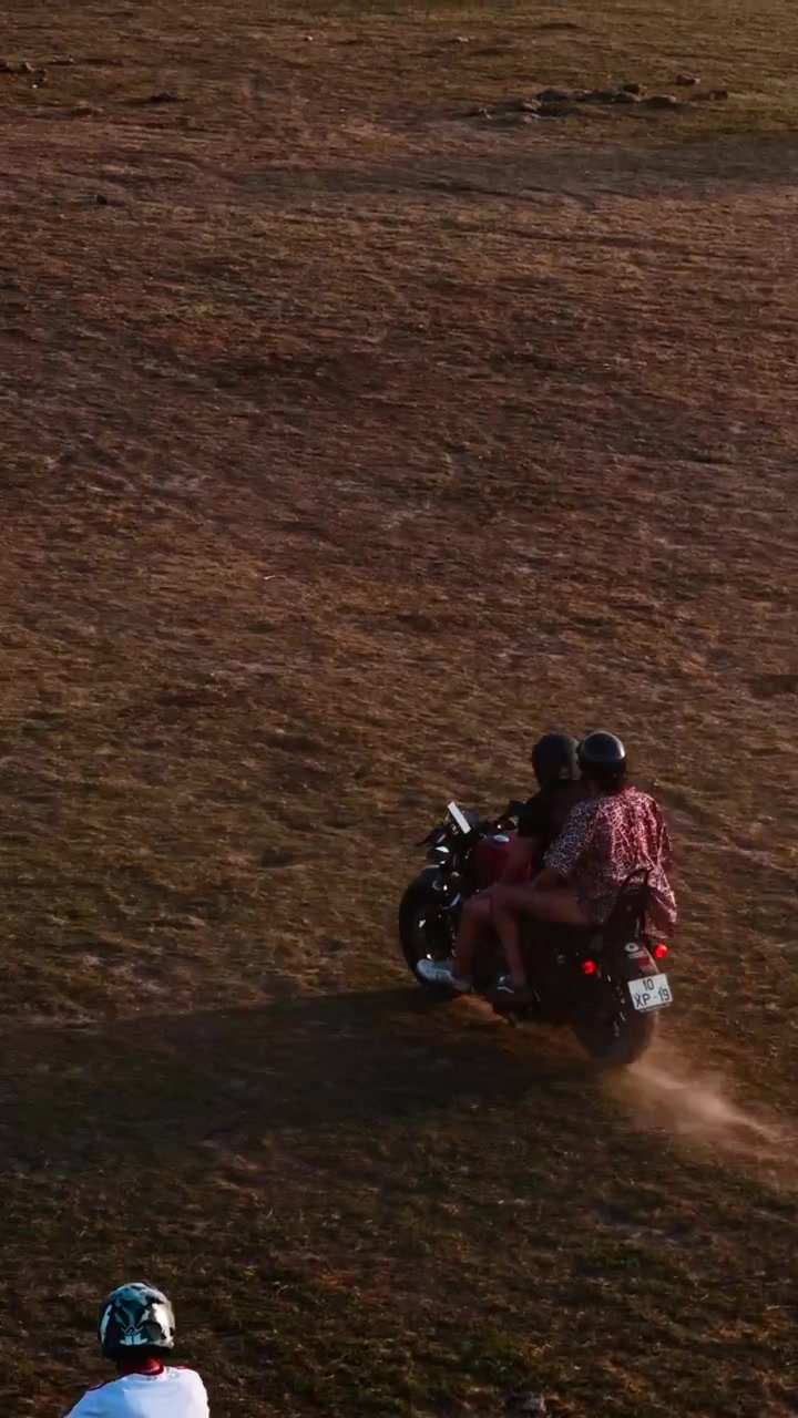 Due persone in moto attraverso un campo polveroso al tramonto