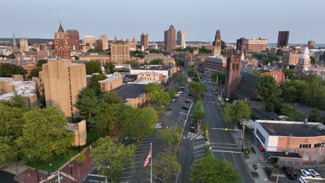 aerial view of downtown new haven, connecticut, showing historic churches, yale university buildings and modern skyscrapers in warm evening light. waving american flag in proud city. wide shot