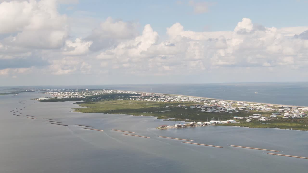 An aerial shot of Grand Isle, Louisiana, overlooking the middle and east end of the island. It includes views of residential areas, undeveloped land, the water tower, and more