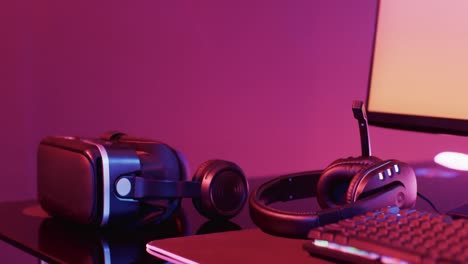 video of computer and gaming equipment on desk with copy space on neon background