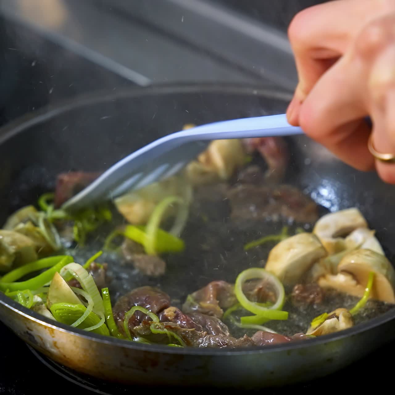 Mushrooms fried with vegetablesin a big frying pan. Chef turns fried ingredients with spatula