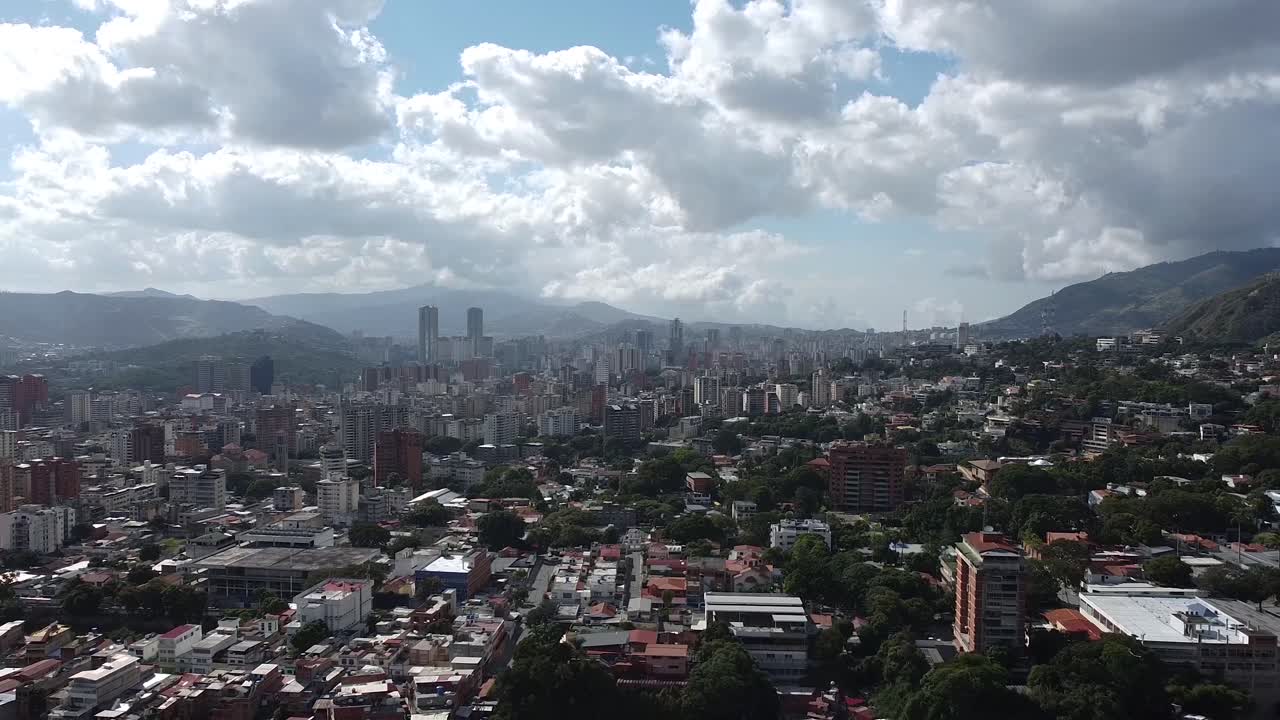 Veduta aerea del centro di Caracas, Venezuela, colline ondulate, nuvole che si addensano, pieno sole, carrellata indietro