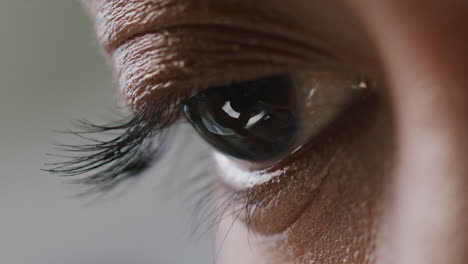 extreme close up of eye of scientist looking through microscope