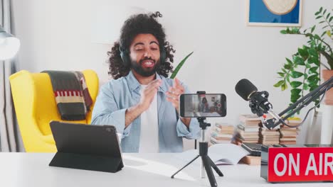 young sociable arabian man applauds recording video blog on mobile phone