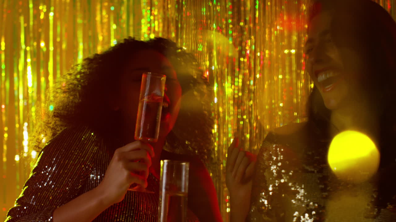 cerca de dos mujeres bailando en un bar de club nocturno o discoteca bebiendo alcohol con luces brillantes 16