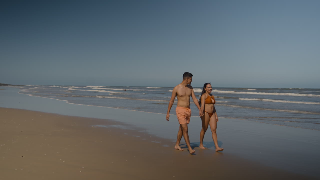 una pareja linda caminando por la playa.