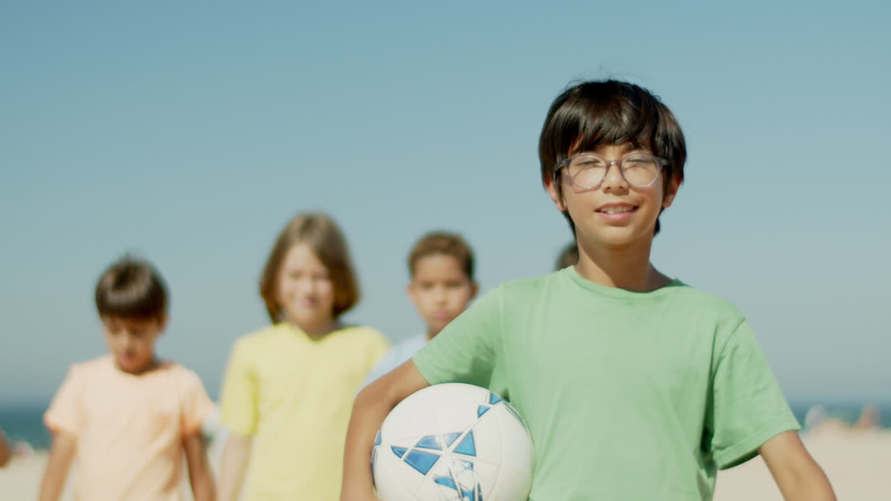 해변 에 서서 공 을 들고 있는 행복 한 소년 의 앞면