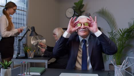 hombre gracioso en traje cubriendo sus ojos con monedas de oro