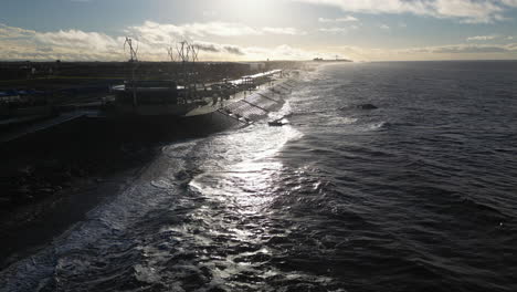 Slow-motion-waves-crashing-against-sea-defences-with-people-walking-in-winter-at-Cleveleys