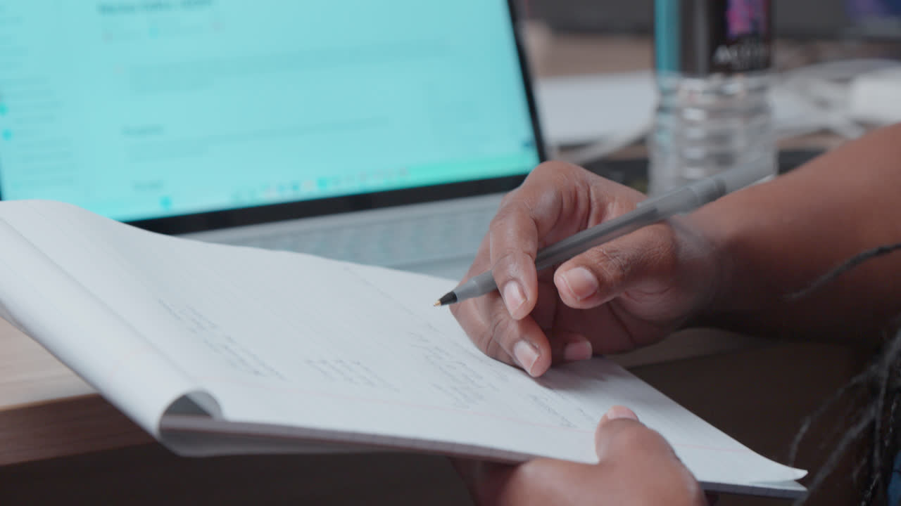 Professionista che prende appunti su carta mentre lavora con il laptop in ufficio