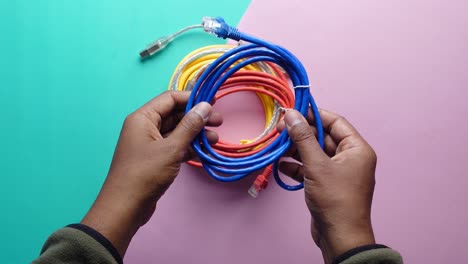 manos sosteniendo cables de red de colores