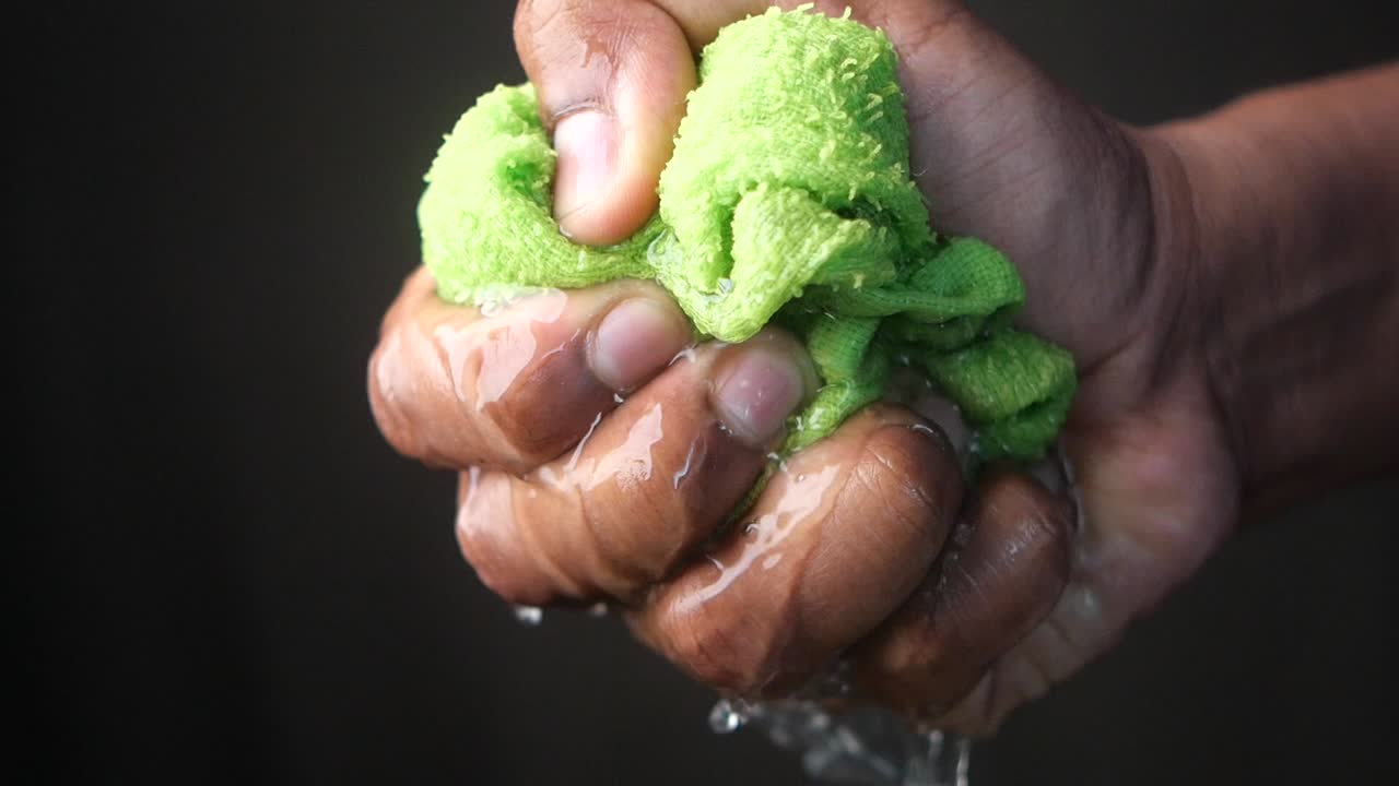 la mano apretando una toalla verde húmeda