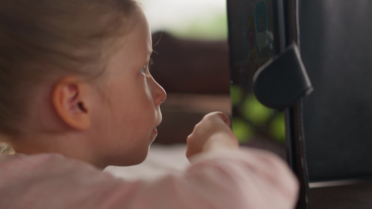 Tranquil little child plays on tablet PC at table in cafe