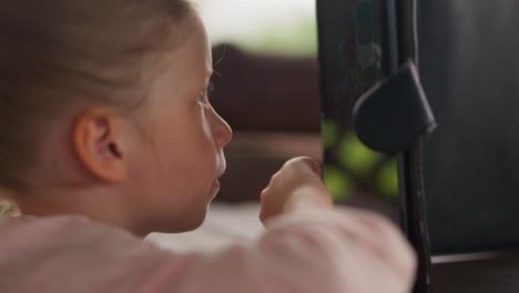 tranquil little child plays on tablet pc at table in cafe