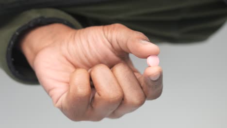 hand holding a pink pill