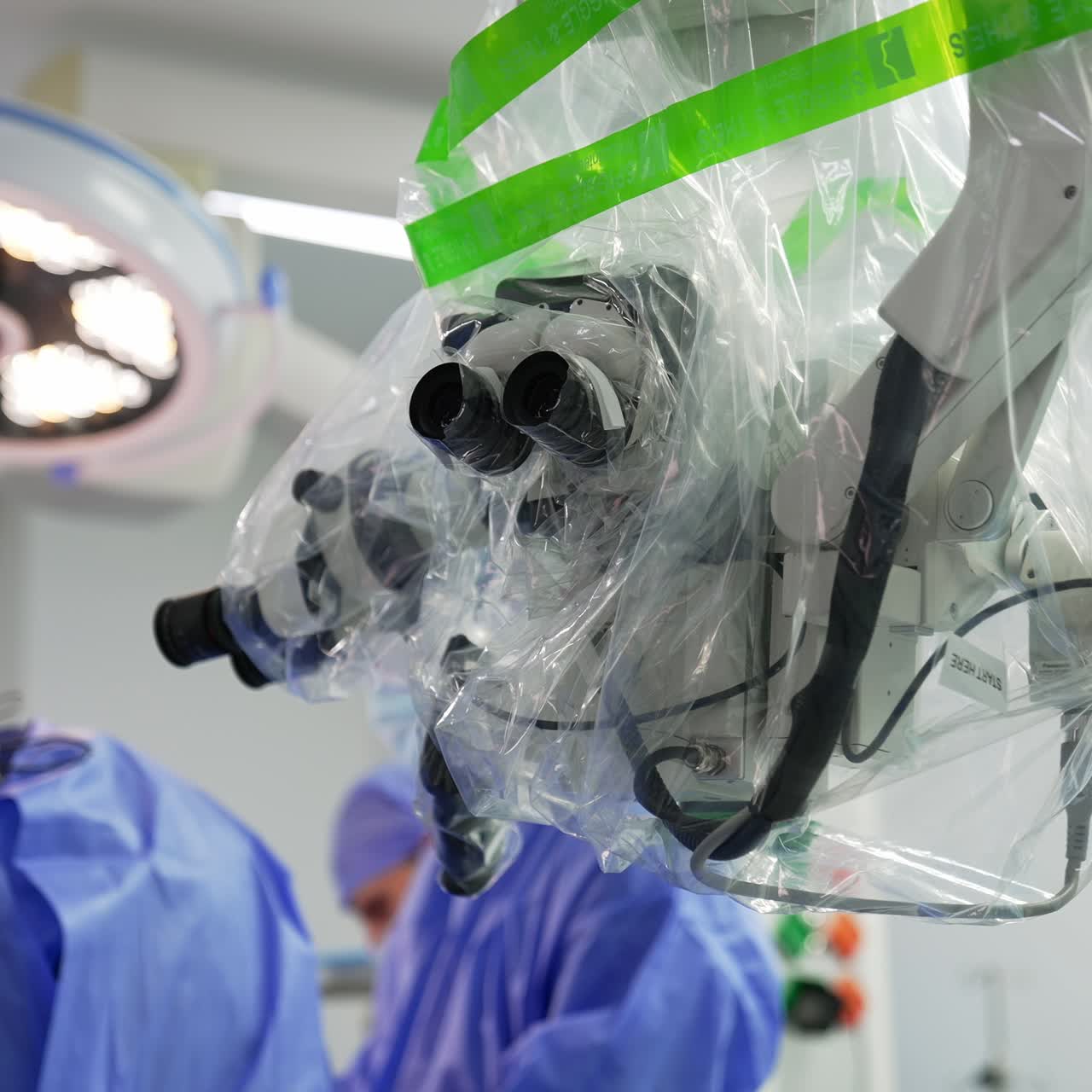 Advanced surgery equipment coated with plastic in operational room. Surgeon's team operating the patient at backdrop in blur