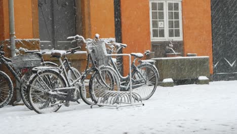 snowing in city, snowflakes falling on standing bikes in copenhagen