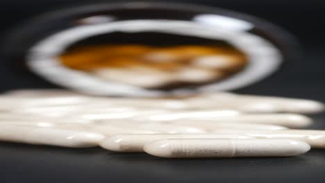 white capsules in front of a dark brown jar