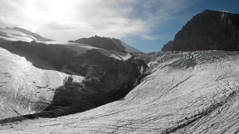 aerial flyover over the ice of the allalin glacier near saas-fee in valais, switzerland with a hiker enjoying the sunny day in the swiss alps