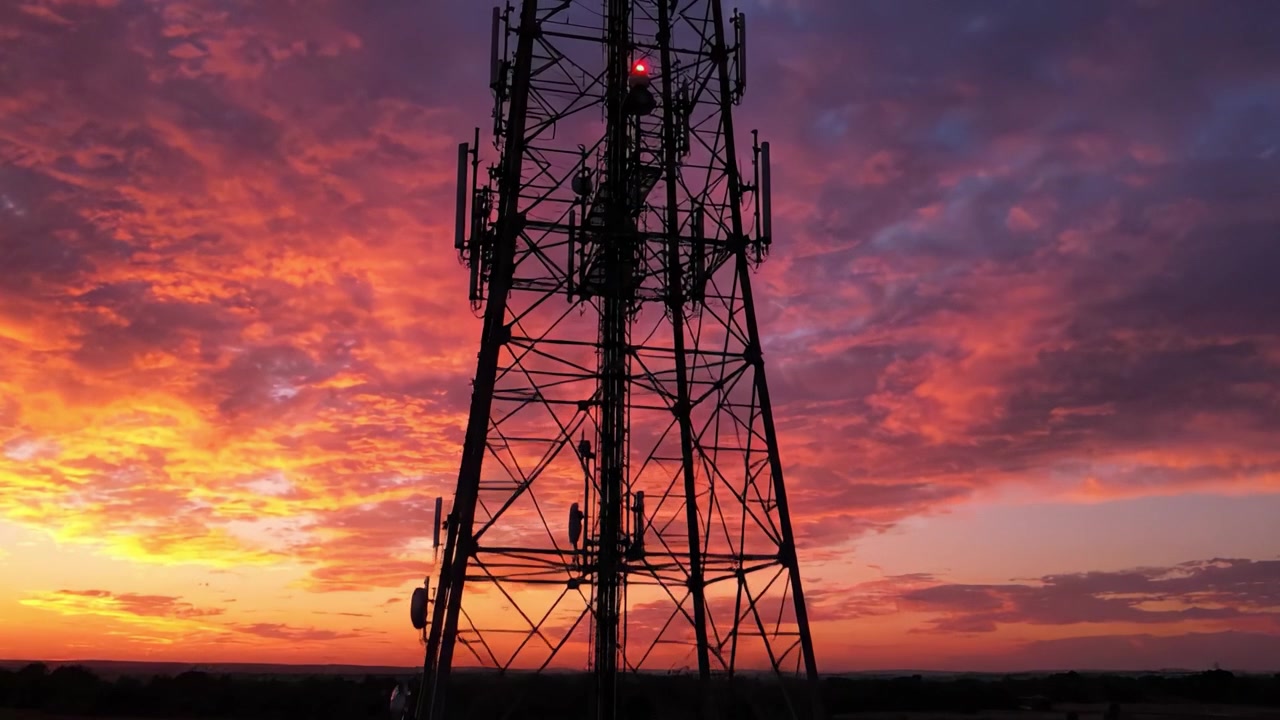 Un Tramonto Mozzafiato Dietro una Torre di Comunicazione, che Mostra Colori Vivaci che si Fondono nel Cielo Mentre il Giorno si Trasforma in Notte, Evidenziando la Bellezza della Natura e della Tecnologia