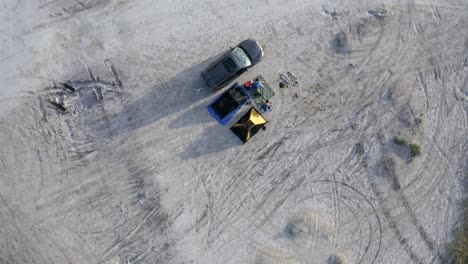 Campers-in-desert-awake-with-long-shadows-aerial-spinning-drop-shot