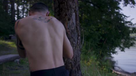 hombre entrenando boxeo al aire libre junto a un lago