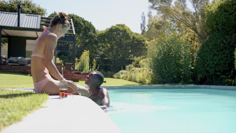 relaxing by pool, diverse couple enjoying sunny day together in backyard, copy space