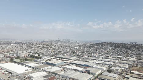 this pull out drone shot offers a sunny, scenic vista of san francisco's bayview neighborhood, commercial and residential areas, downtown skyline, and yerba buena island, all vibrant bay activity