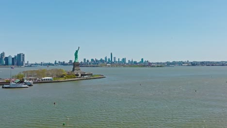 aerial panorama view of statue of liberty in foreground and brooklyn district and manhattan skyline in background