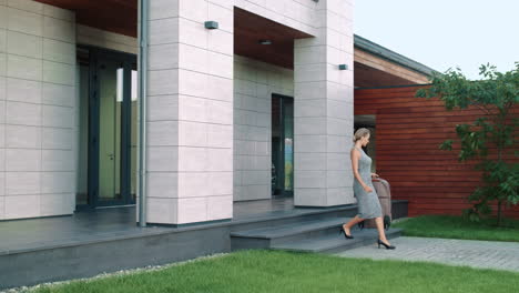 Business-woman-holding-suitcase-near-luxury-house.-Business-woman-leaving-hotel.