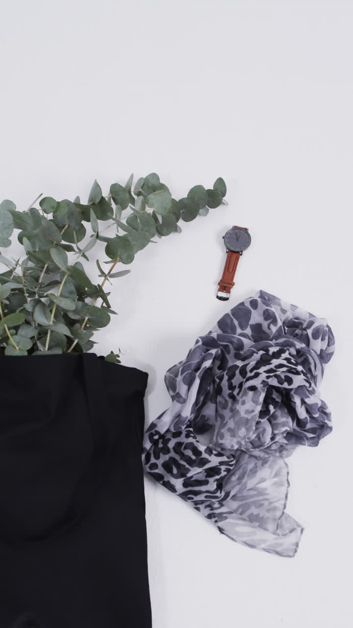 Vertical video of black canvas bag with plant, scarf, watch, copy space on white background