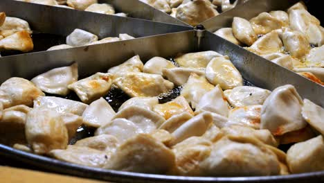 street food. polish dish - pierogi, frying in hot oil in a large skillet