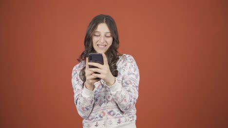 행복한 젊은 여성이 전화로 문자 메시지를 보내고 웃고 있습니다.