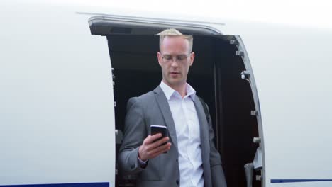 businessman talking on mobile phone while moving out from private jet 4k