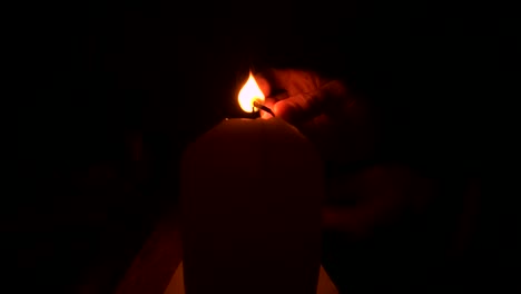 lighting a candle with a match in the dark