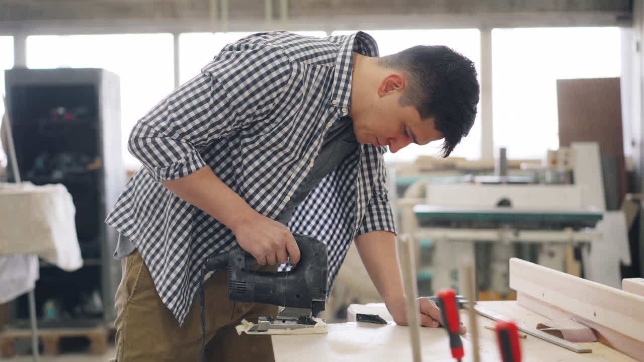 ผู้ชายกำลังใช้เลื่อยจิ๊กซอว์ในห้องทำงาน